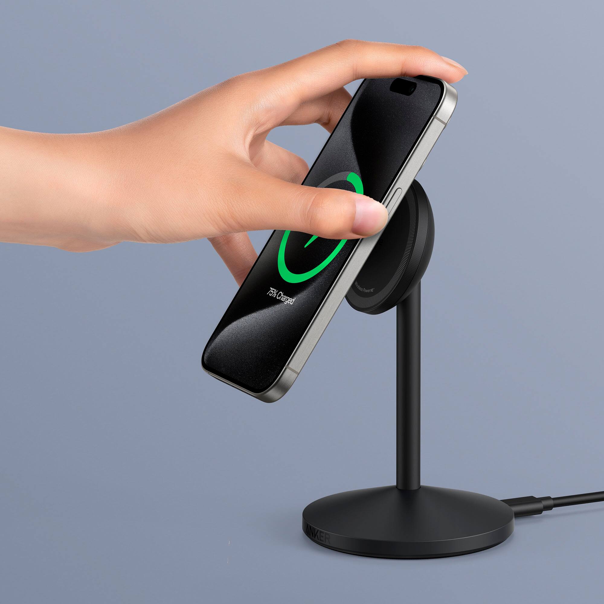 The image shows a person holding a smartphone next to a charging station. The charging station has a green light, indicating that the phone is 75% charged. The person is likely using the Anker charger to charge their phone.