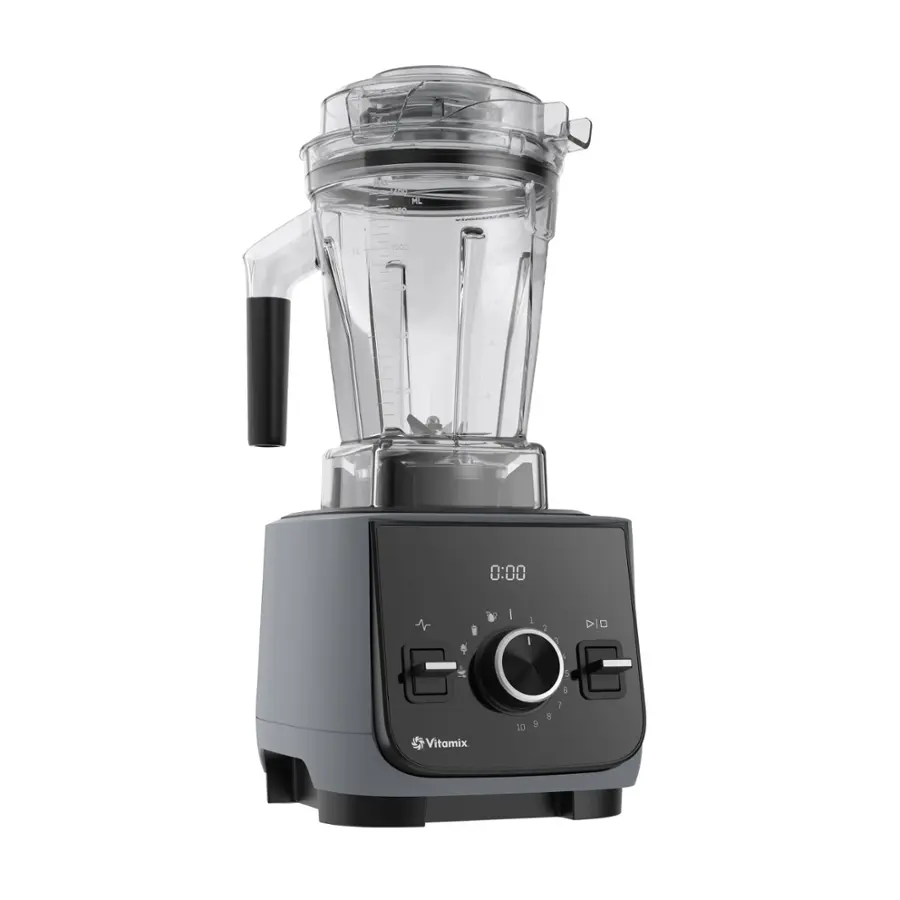 The image shows a Vitamix blender with a clear container and black handle. The blender is turned on and ready to blend.