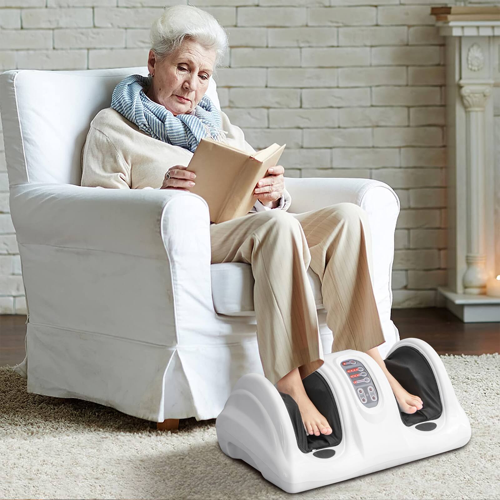 The image shows an elderly woman sitting in a chair, reading a book. She is wearing a scarf and has her feet on a foot massager. The chair she is sitting on is white, and there is a fireplace in the background. The woman appears to be enjoying her time, relaxing and reading her book while having her feet massaged.