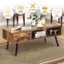 The image features a wooden coffee table with a retro appearance. The table is made of premium material and is easy to assemble. It has a stable structure and is versatile in use. On the table, there are several items such as a vase, a cup, a book, and a bottle. The table is placed on a rug, and there are chairs nearby. The image also includes a diagram explaining the table's features and benefits.
