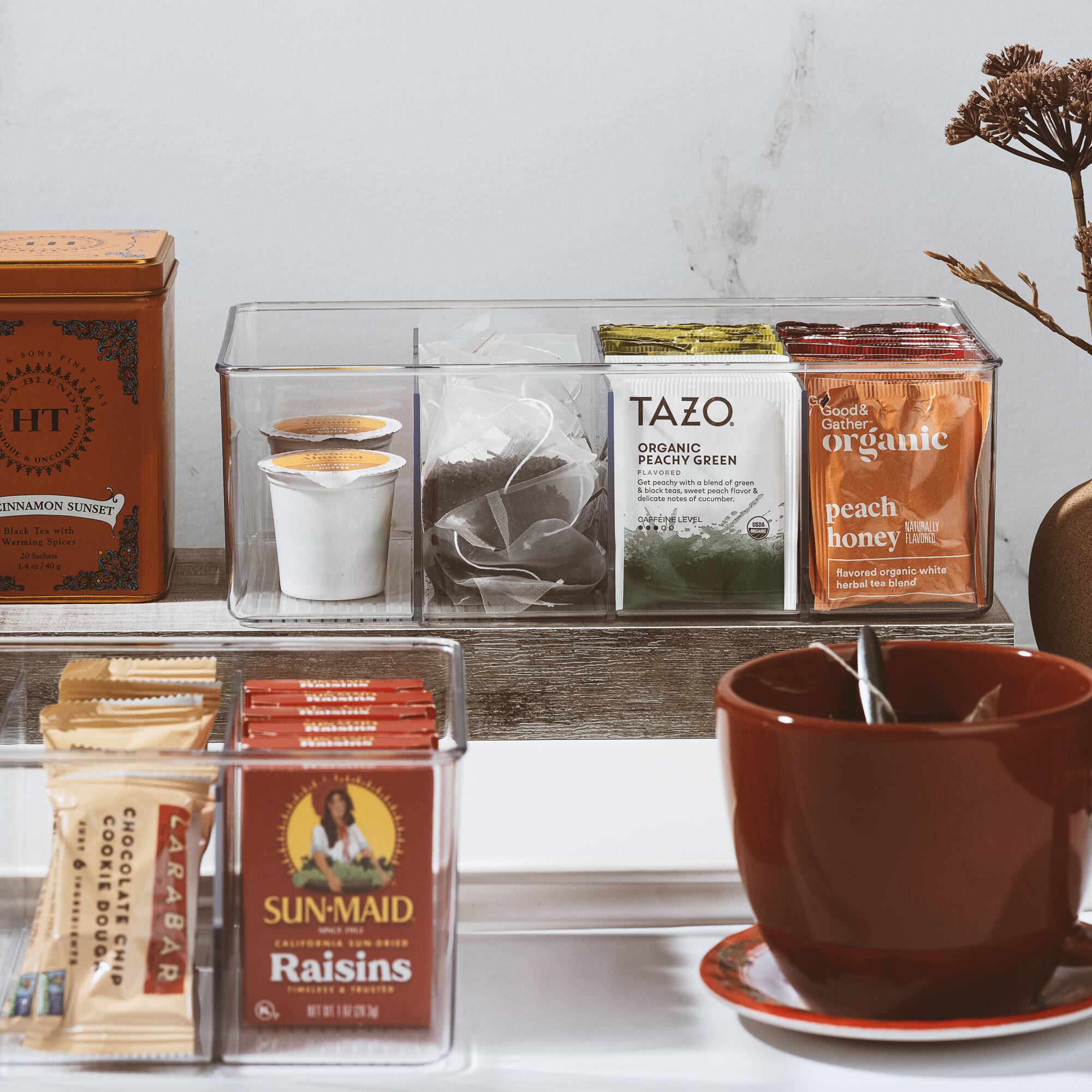 Sure, here is the corrected and grouped text from the image:

---

**SUNSET CINNAMON SUNSET**  
Black Tea With Warming Spices

**TAZO**  
ORGANIC PEACHY GREEN  
Get peachy with a blend of green tea and a hint of peach, honey, and cucumber.  
CAFFEINE LEVEL: LOW

**Good & Gather**  
organic peach honey  
flavored organic white herbal tea blend

**LARABAR**  
COOKIE CHOCOLATE CHIP

**SUN-MAID**  
CALIFORNIA RAISINS

---

This text is organized based on the labels and packaging visible in the image.