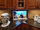 TV in a darker kitchen with white appliances, click to load a larger version