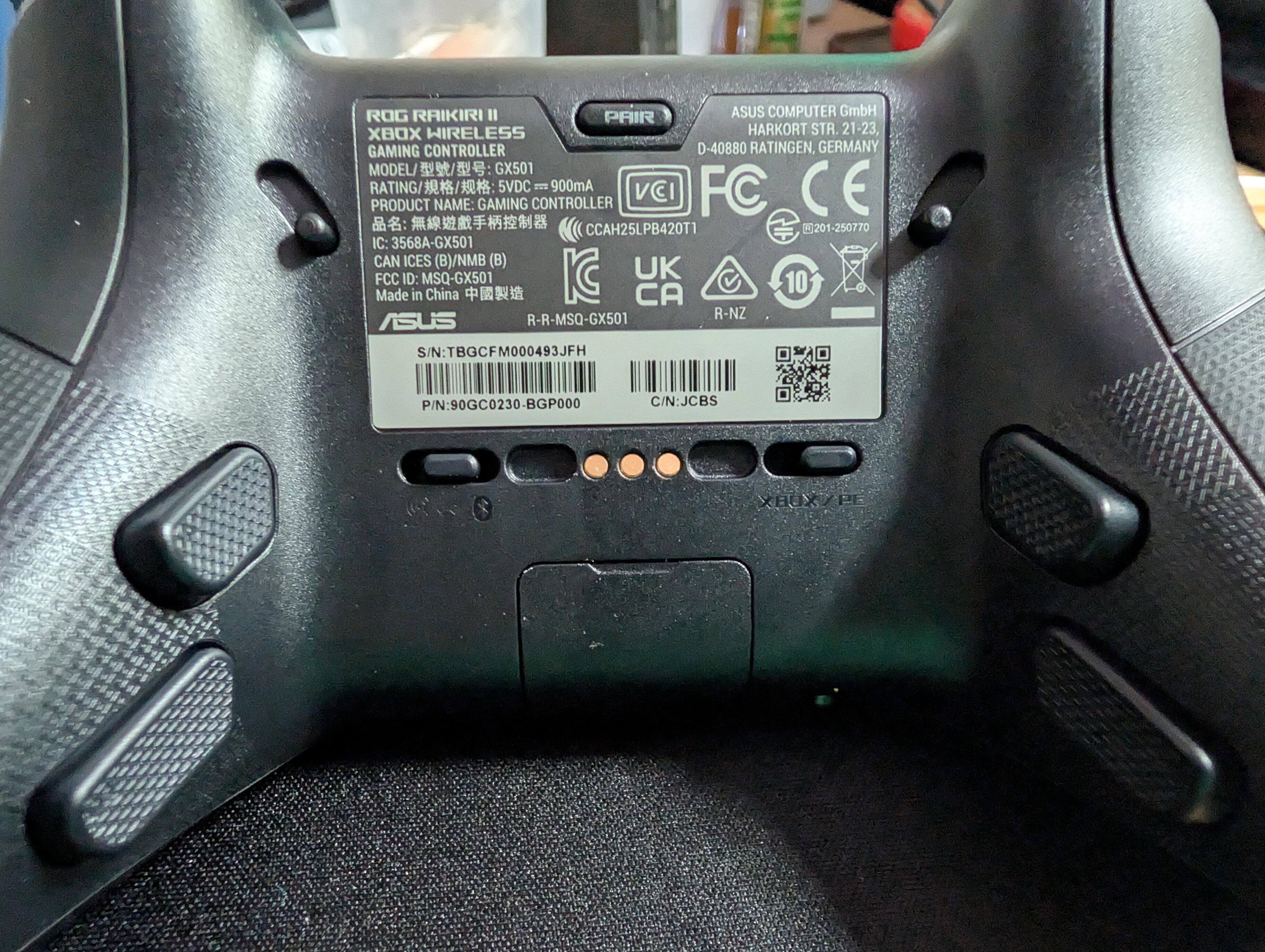The back of the controller, showing the trigger adjustments, connectivity sliders, four extra grip triggers, and the door for storing the wireless USB dongle., click to load a larger version