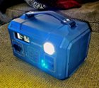 The Fremo is portable, with a handy leather carrying strap. The built-in emergency light is on in this photo.  All available ports (USB/C/AC/DC, etc) are in front as well as a status and battery LCD. Vents are on each side., click to load a larger version