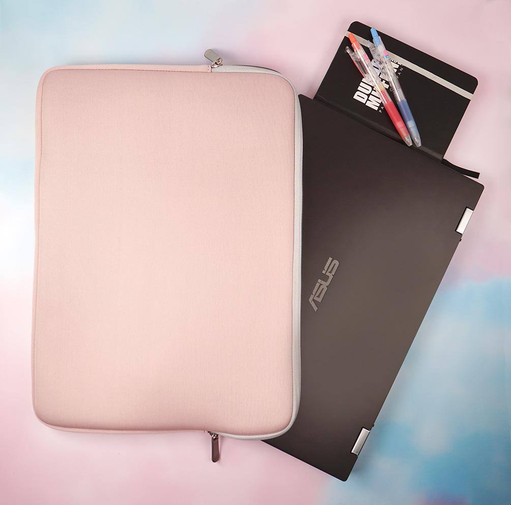 Top down view of a 15.6" laptop peeking half way outside the bag with a small journal and two pens beside it., click to load a larger version