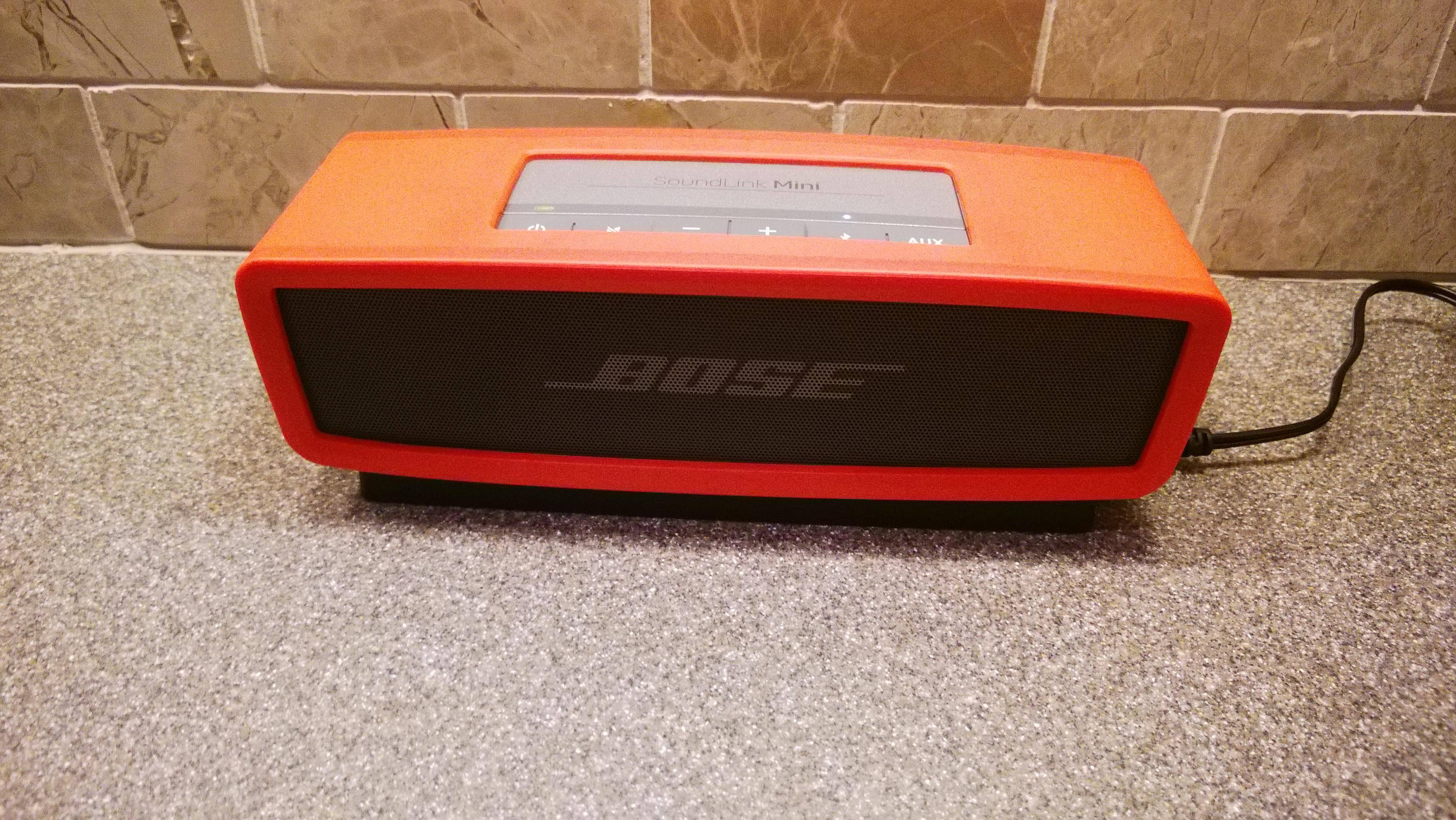 Soundlink Mini in orange case on charging cradle., click to load a larger version